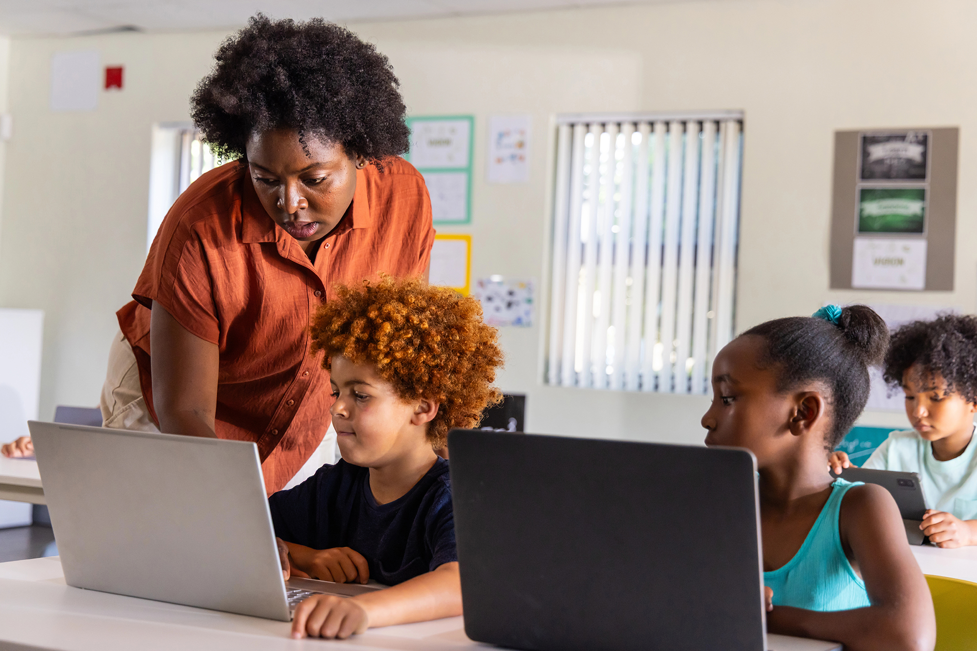 Teacher helping students with laptops